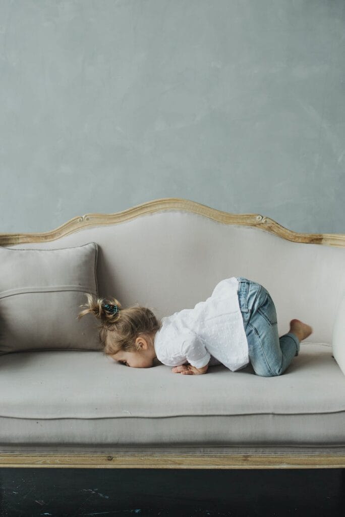 little funny girl playing on sofa